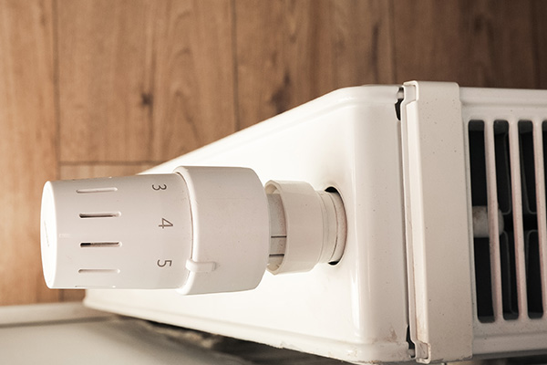 white radiator heater with control dial showing numbers 1 to 5 for temperature setting in a cozy home environment